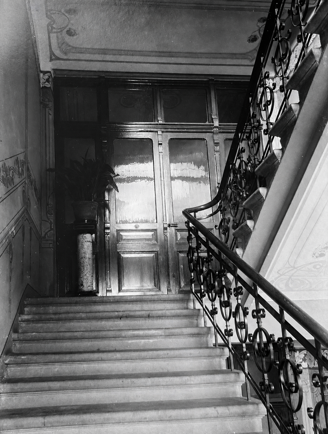 Grand stone staircase with Art Nouveau wrought-iron balustrade and stenciled wall motifs