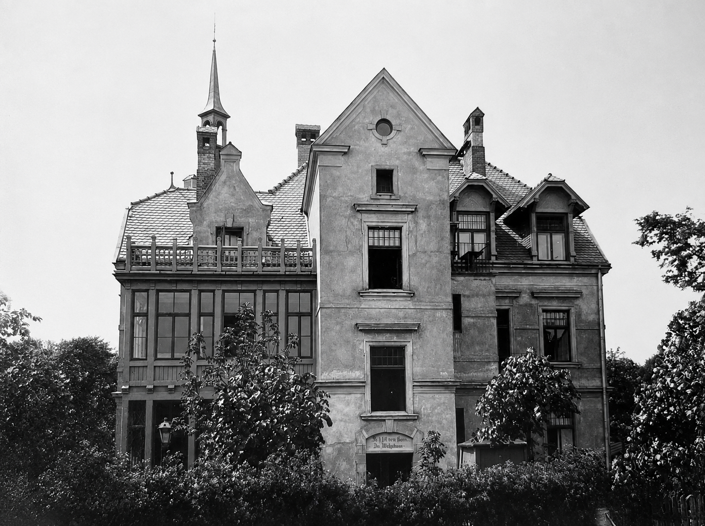 Full garden facade with slate-tiled roof, decorative spires, and Gothic inscription